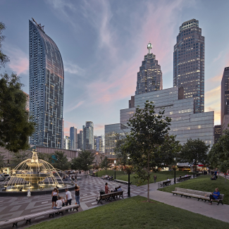 Photo au crépuscule montrant la fontaine et le quartier financier de Toronto dans le cadre du contexte urbain du parc.