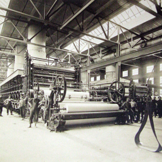 Workers pose with Paper Machines No. 1 and 2 inside the Grand Falls Pulp and Paper Mill, ca. 1910